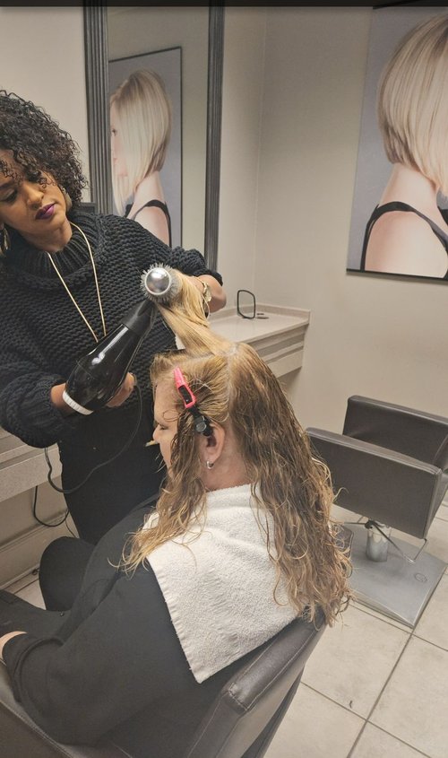 Addi blow drying a woman's hair.