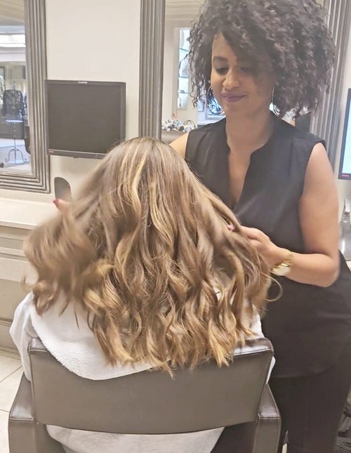 Addi doing a woman's hair with a beach wave style.