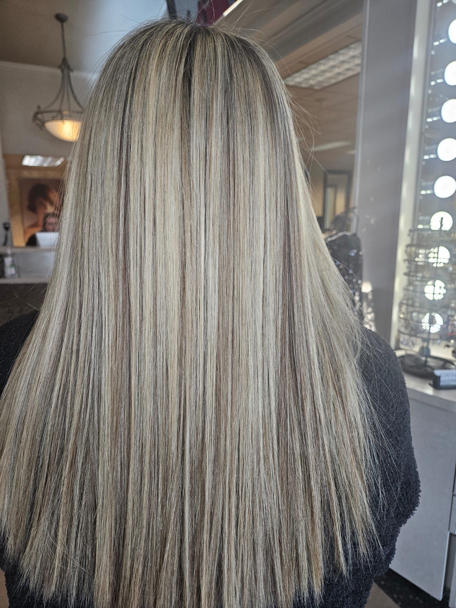 A woman with straight blonde hair after Addi gave her a keratin treatment.