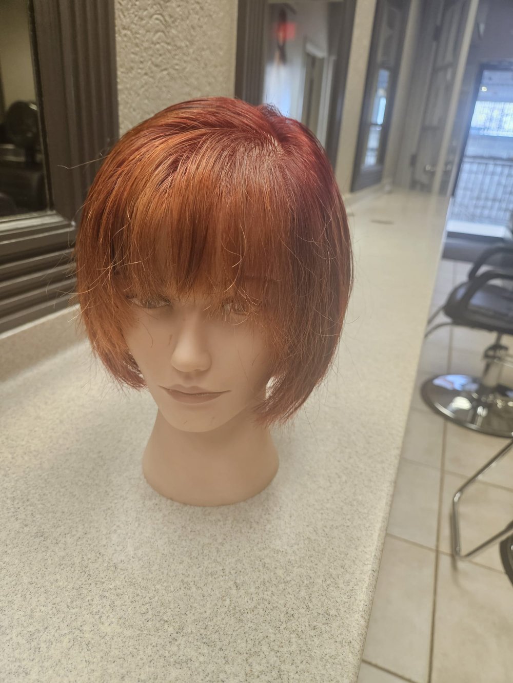 Front view of a short, red wig cut and styled by Addi.